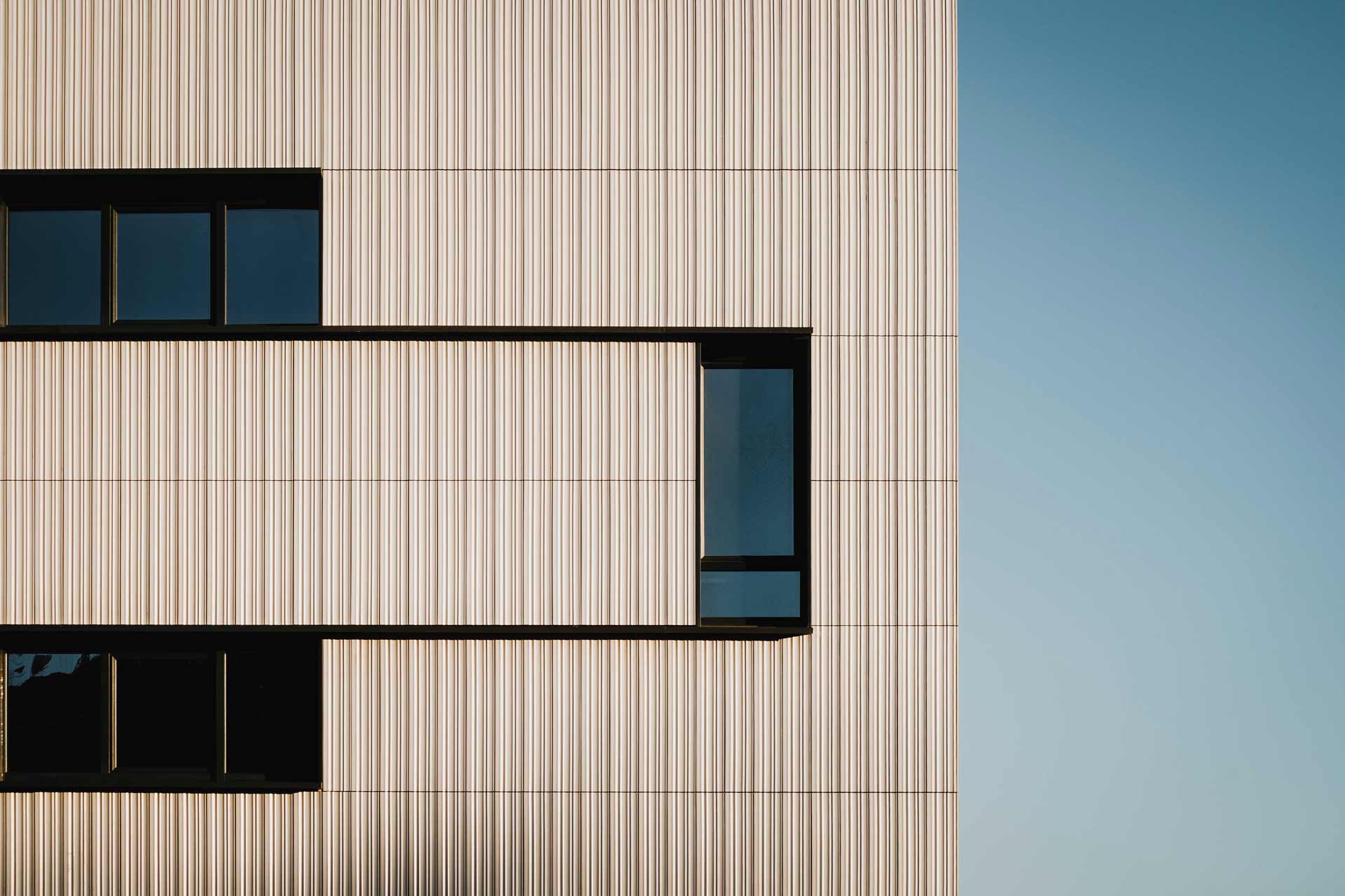 Wellenförmige Fassade eines Gebäudes mit Fenstern.