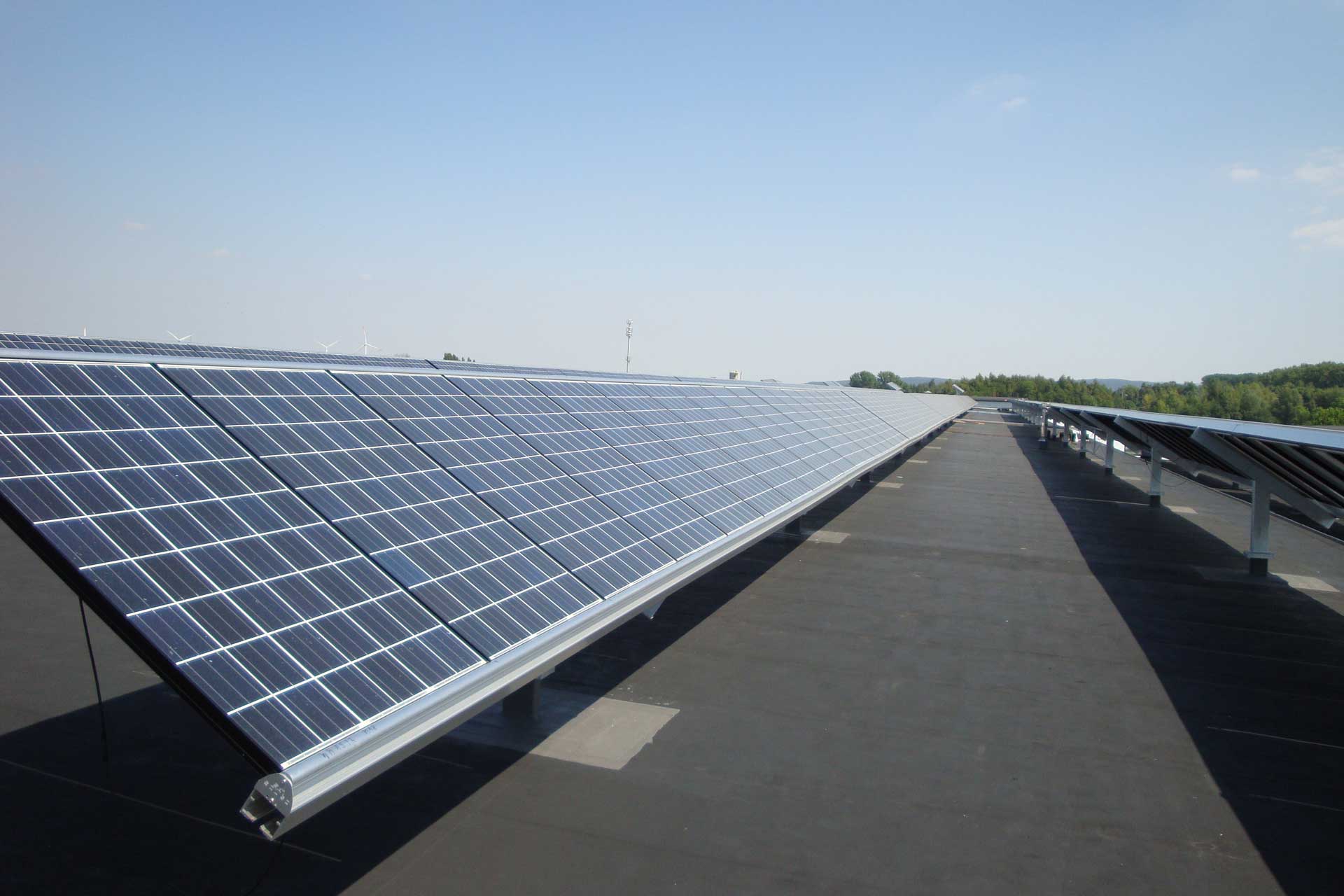 Flachdach mit zwei langen Reihen von Photovoltaikmodulen.