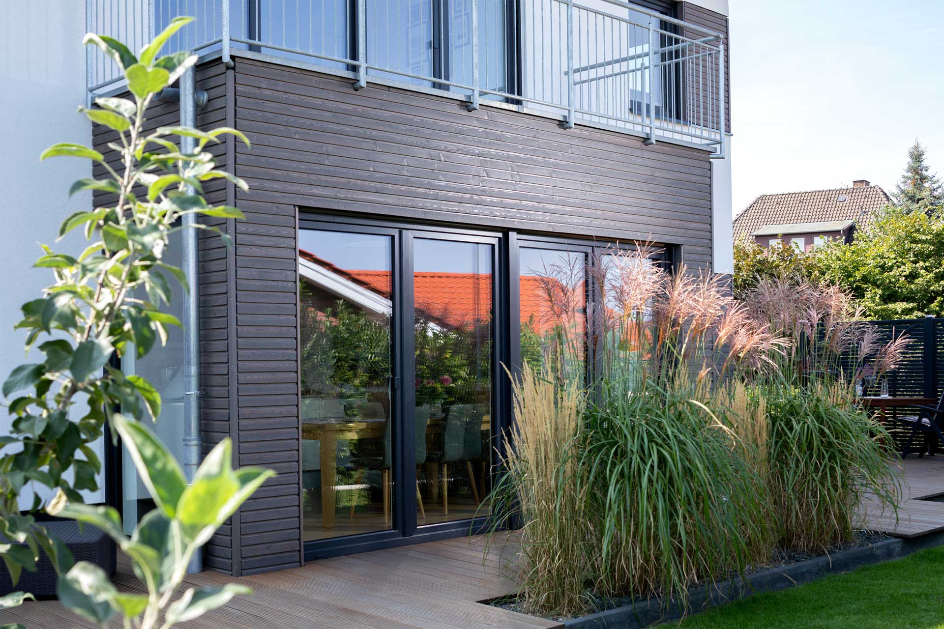 Einfamilienhaus mit holzverkleidetem Erker und Garten.