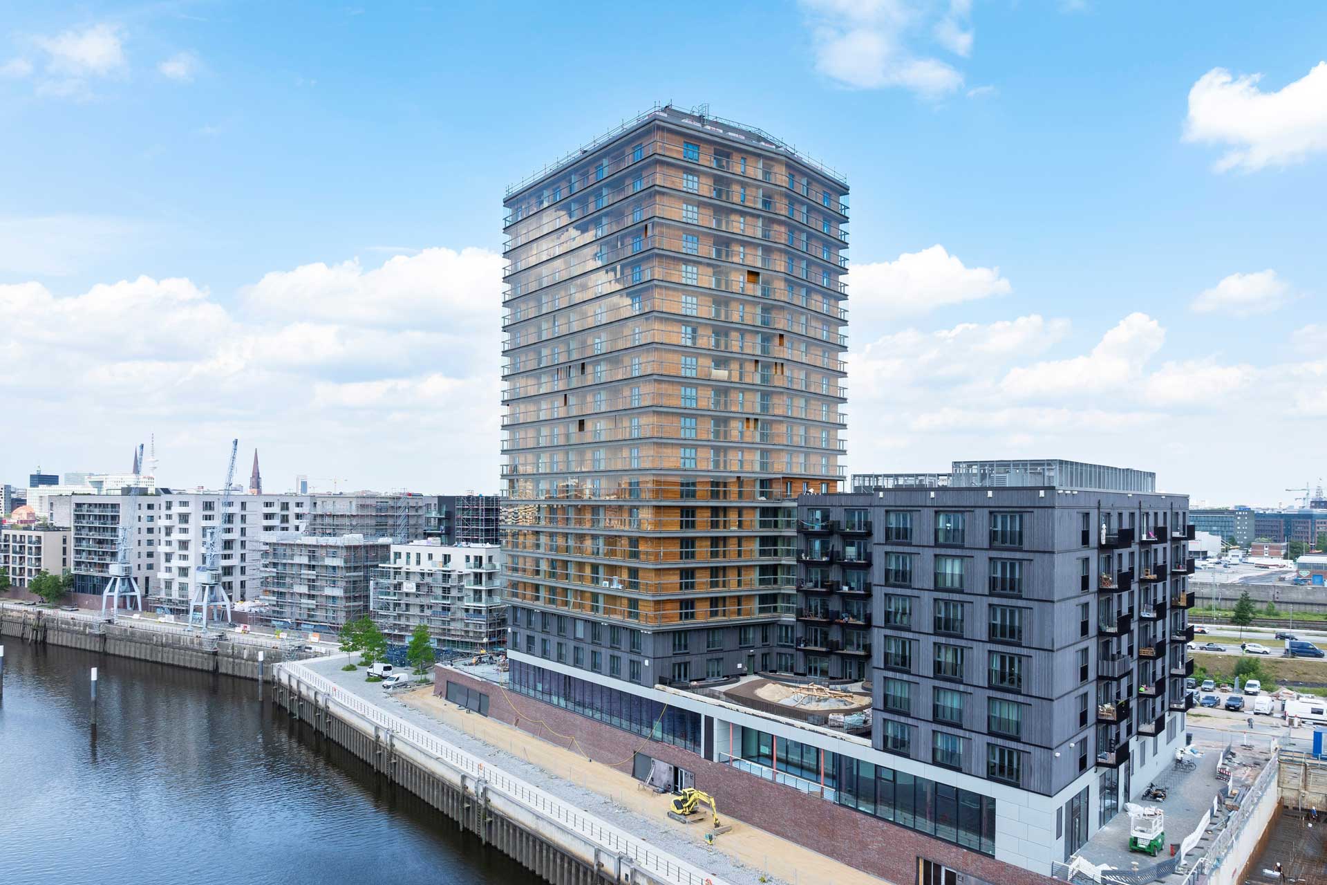 Mehrfamilienhäuser stehen an einem Fluß, darunter ein Hochhaus.