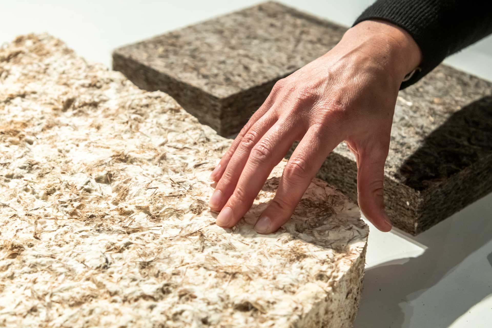 Eine Männerhand berührt einen Block aus gepresstem Material.