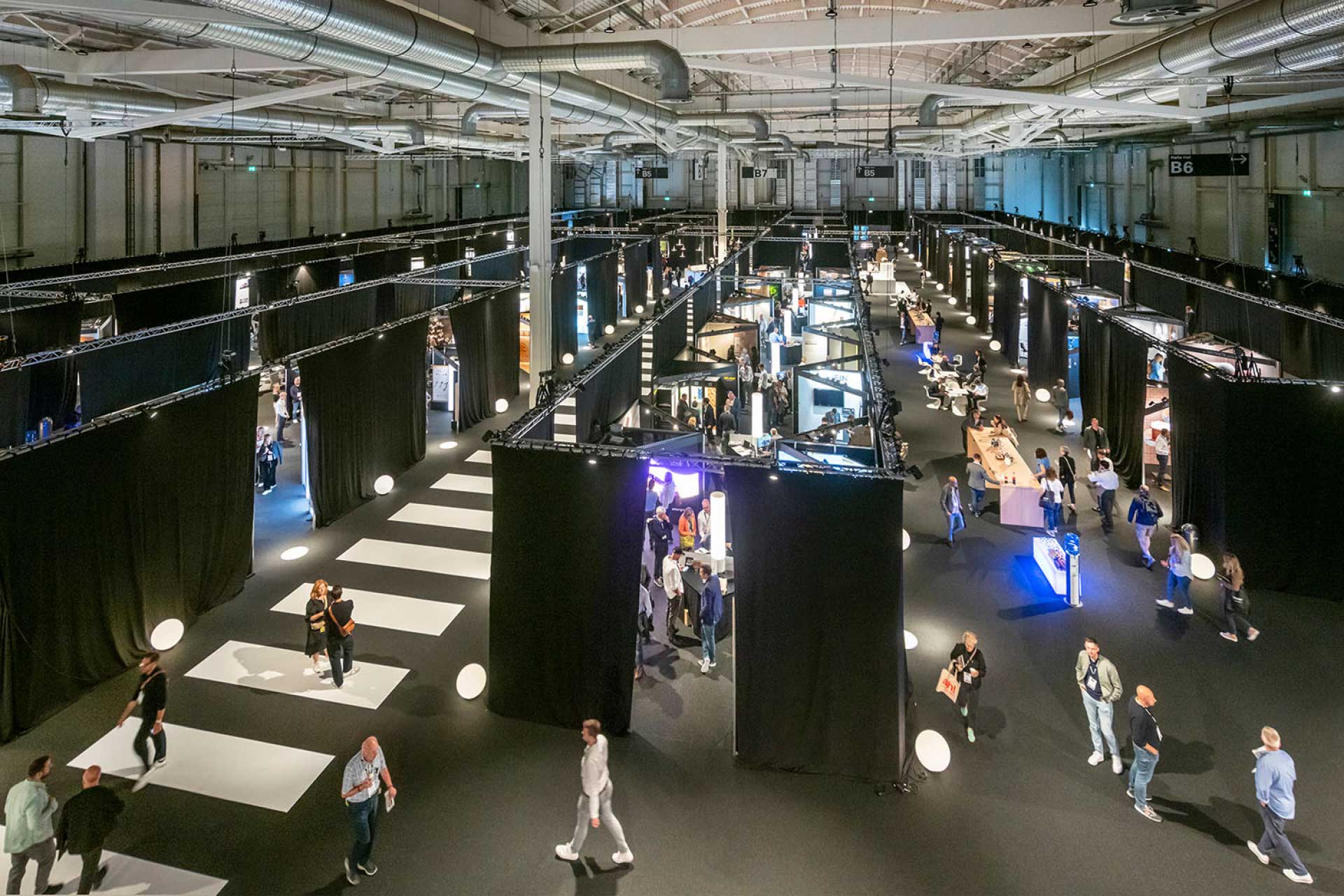 Messehalle mit schwarzem Boden, schwarzen Messest&auml;nden und scharzen W&auml;nden.