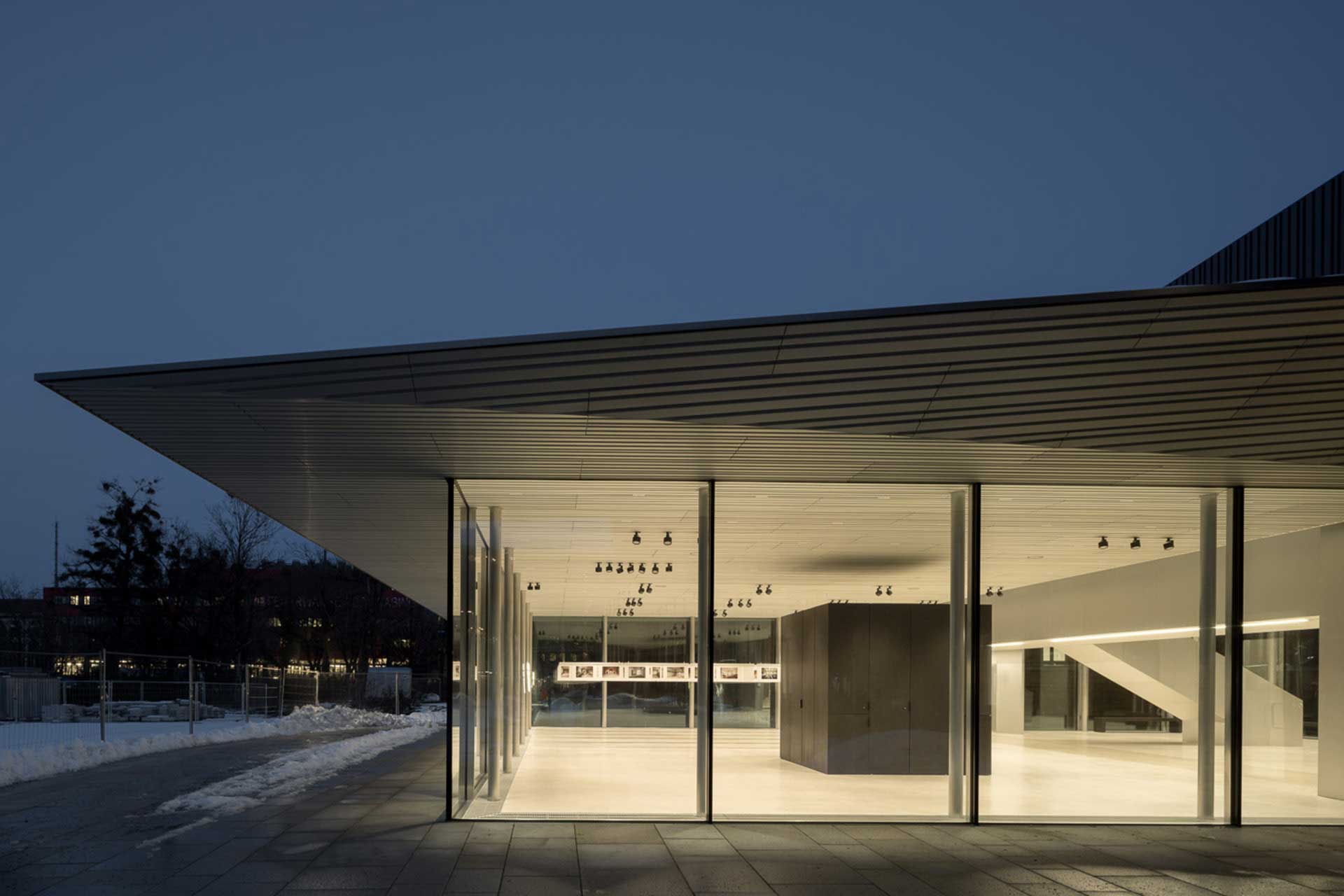 Beleuchteter Ausstellungsraum mit Glasfassade und Flachdach