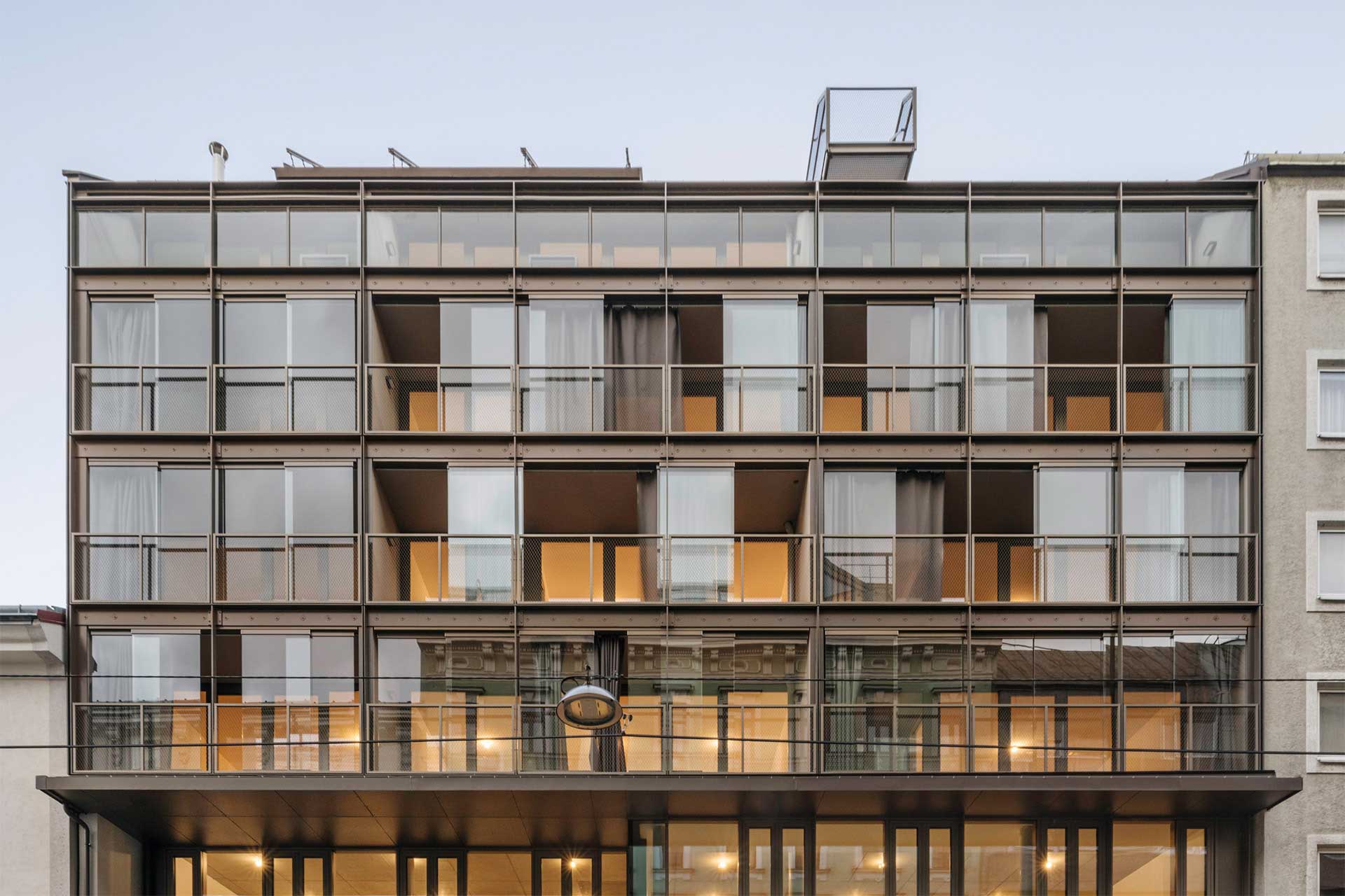 Hausfassade eines Neubaus mit verglasten Balkonen.