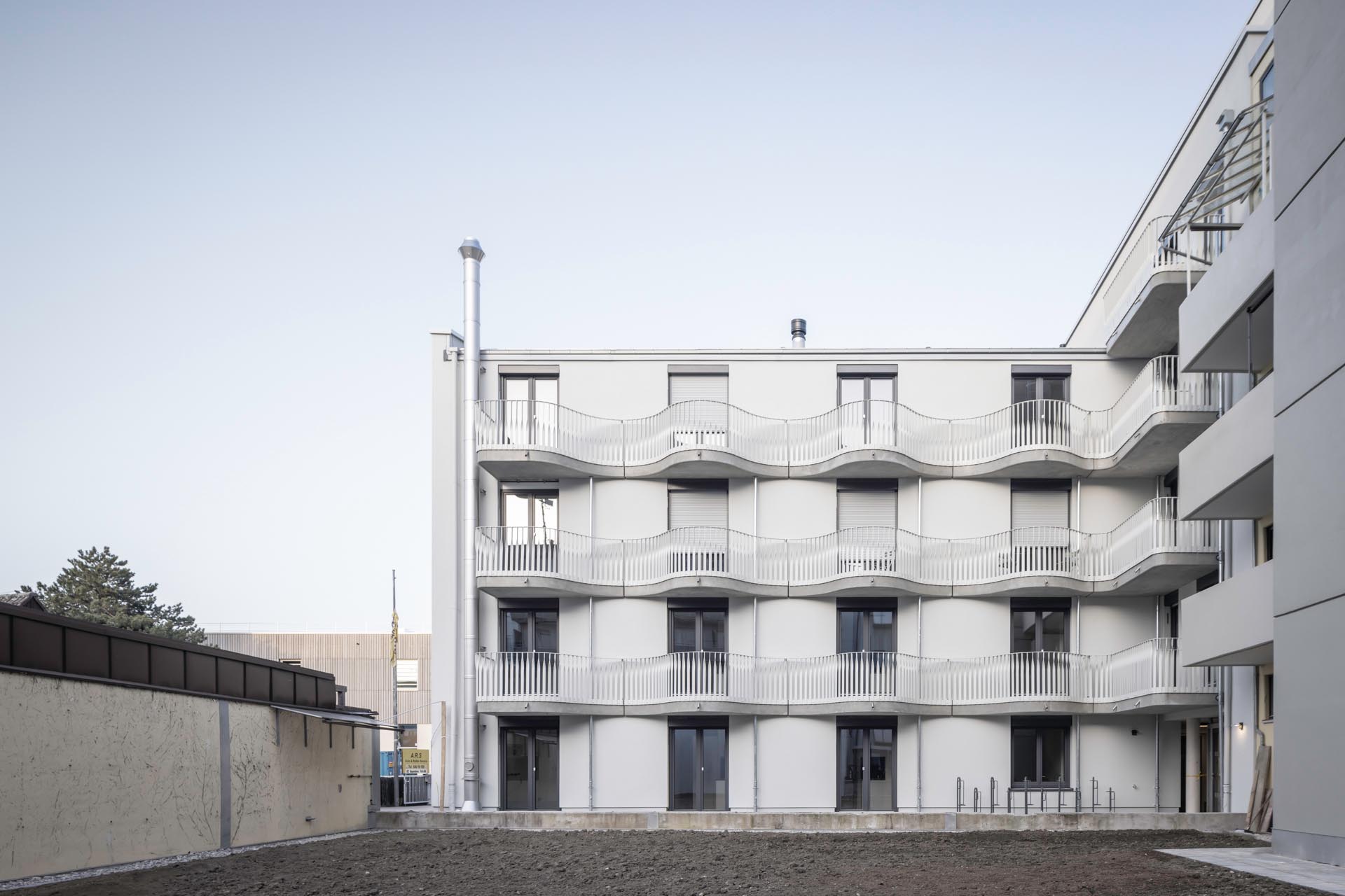 Hinterhofansicht eines Hauses mit geschwungenen Balkonen.