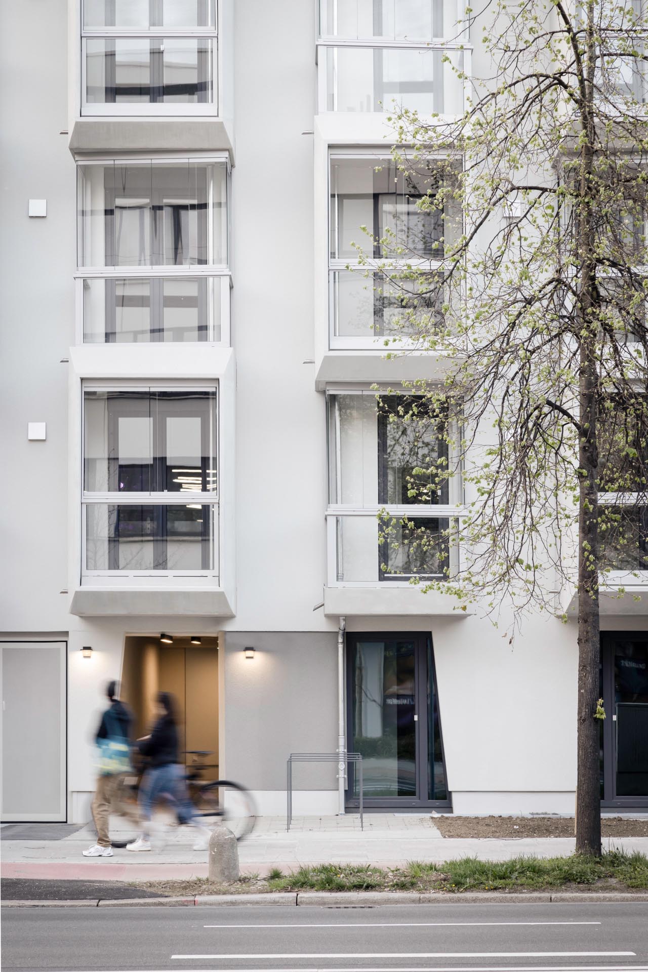 Haus an einer Straße mit schmalen, verglasten Balkonen.