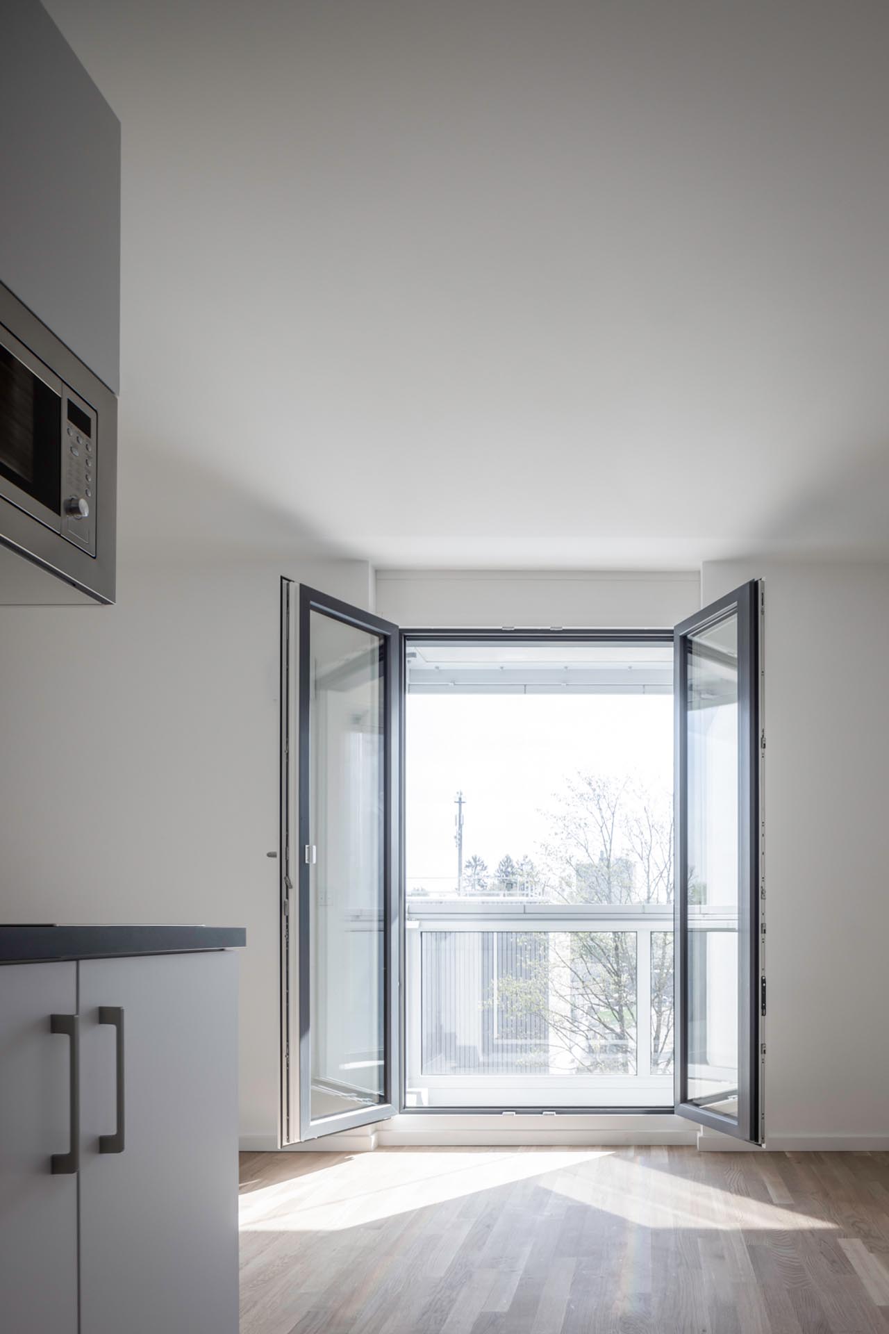 Innenraum mit Küchenzeile und offen stehenden Flügeltüren zum Balkon.